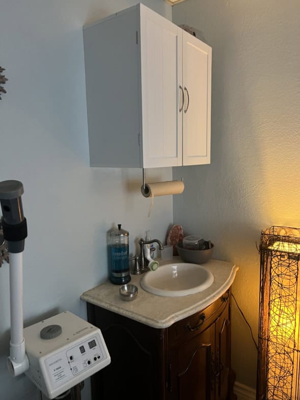Bathroom sink with white cabinet and accessories in salon rental space.