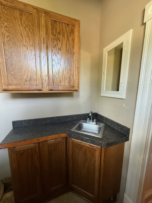 Small kitchen corner with wooden cabinetry and stainless steel sink.
