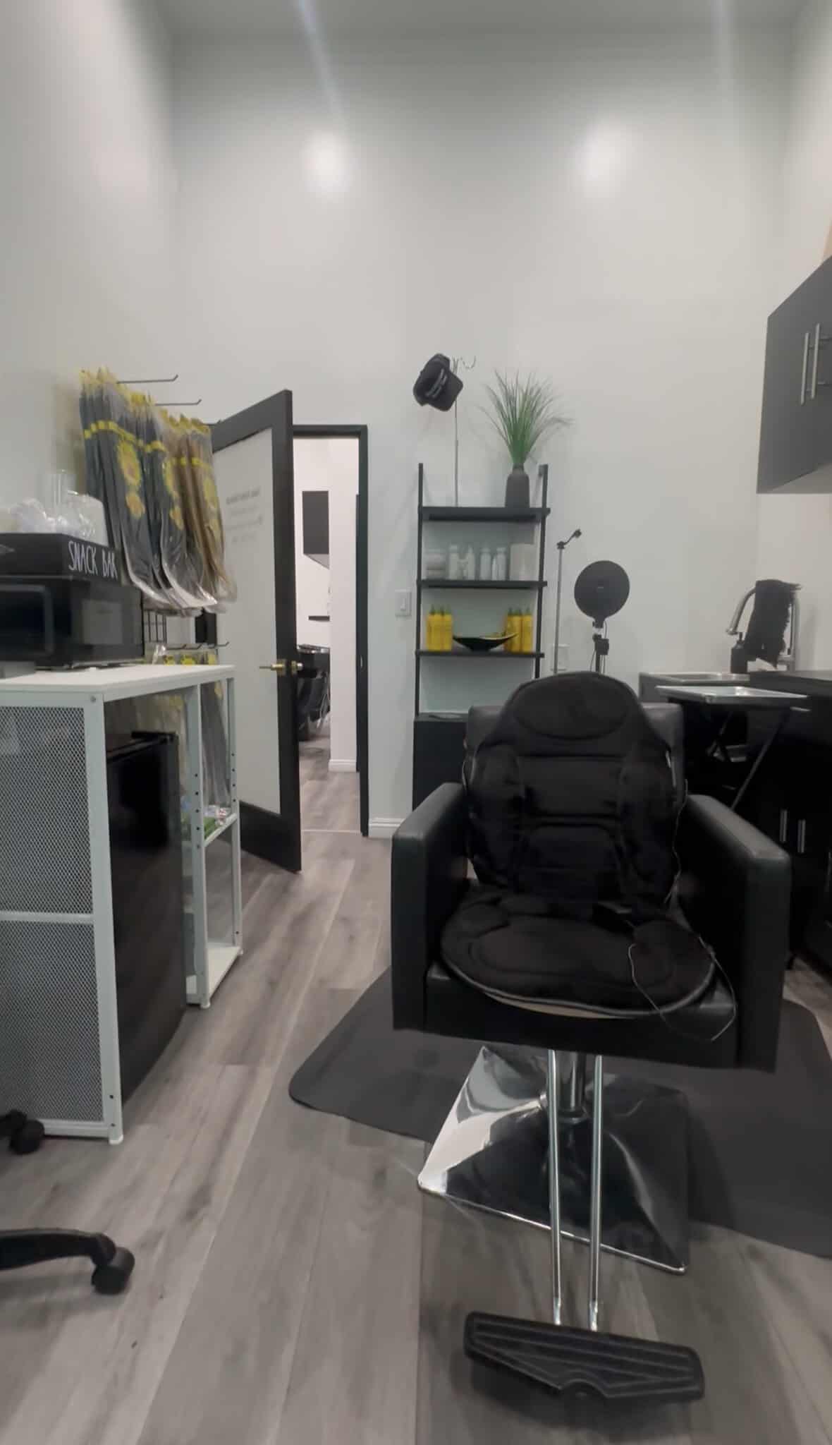 Modern salon interior with styling chair, shelves, and professional equipment.