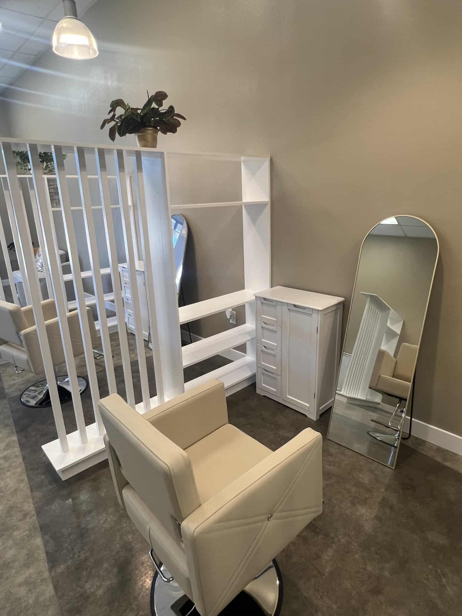 Modern salon space with mirror, chair, and storage cabinet for rent.