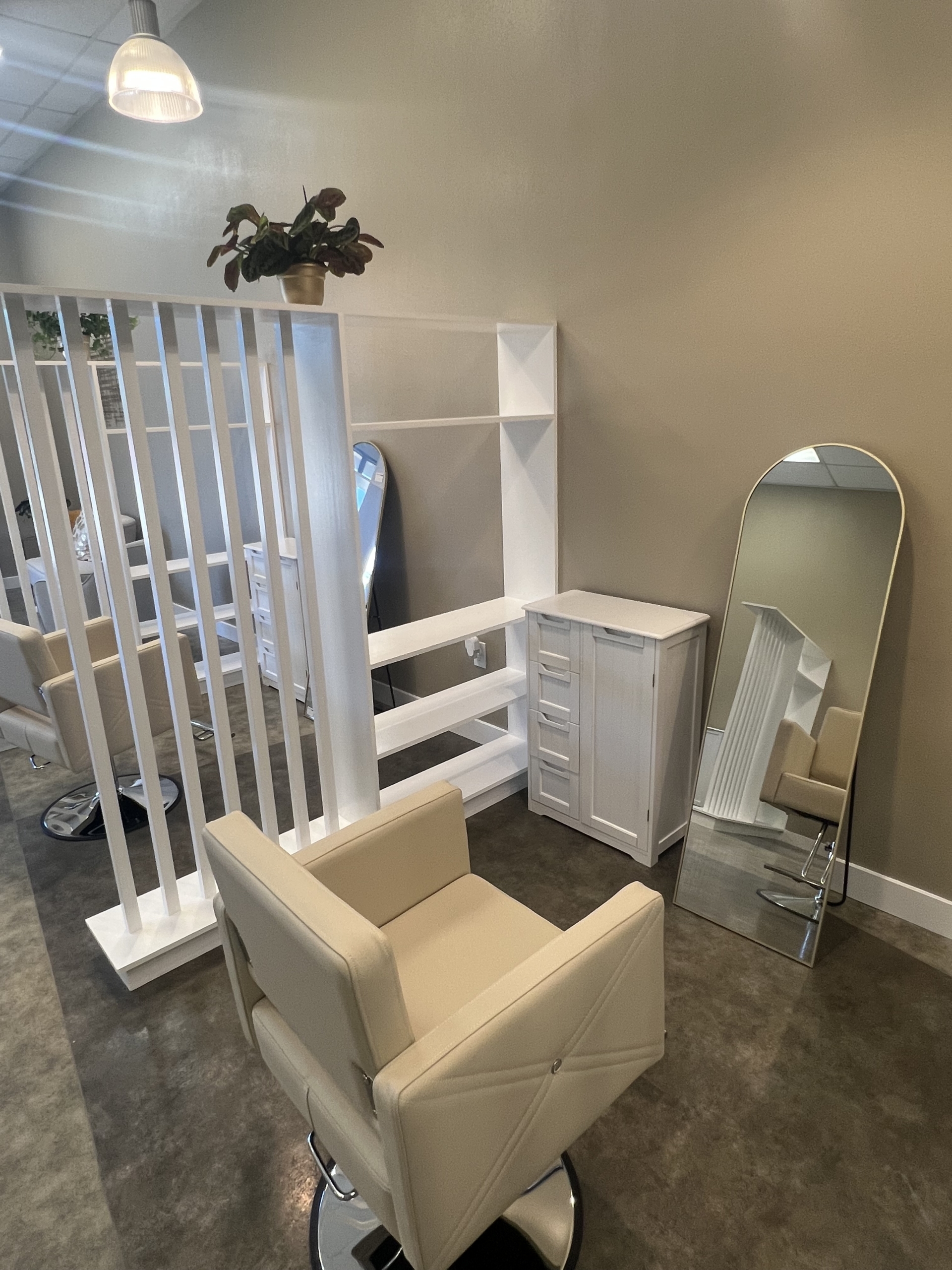 Stylish salon station featuring a large mirror, white storage cabinet, and comfortable chair for hai.