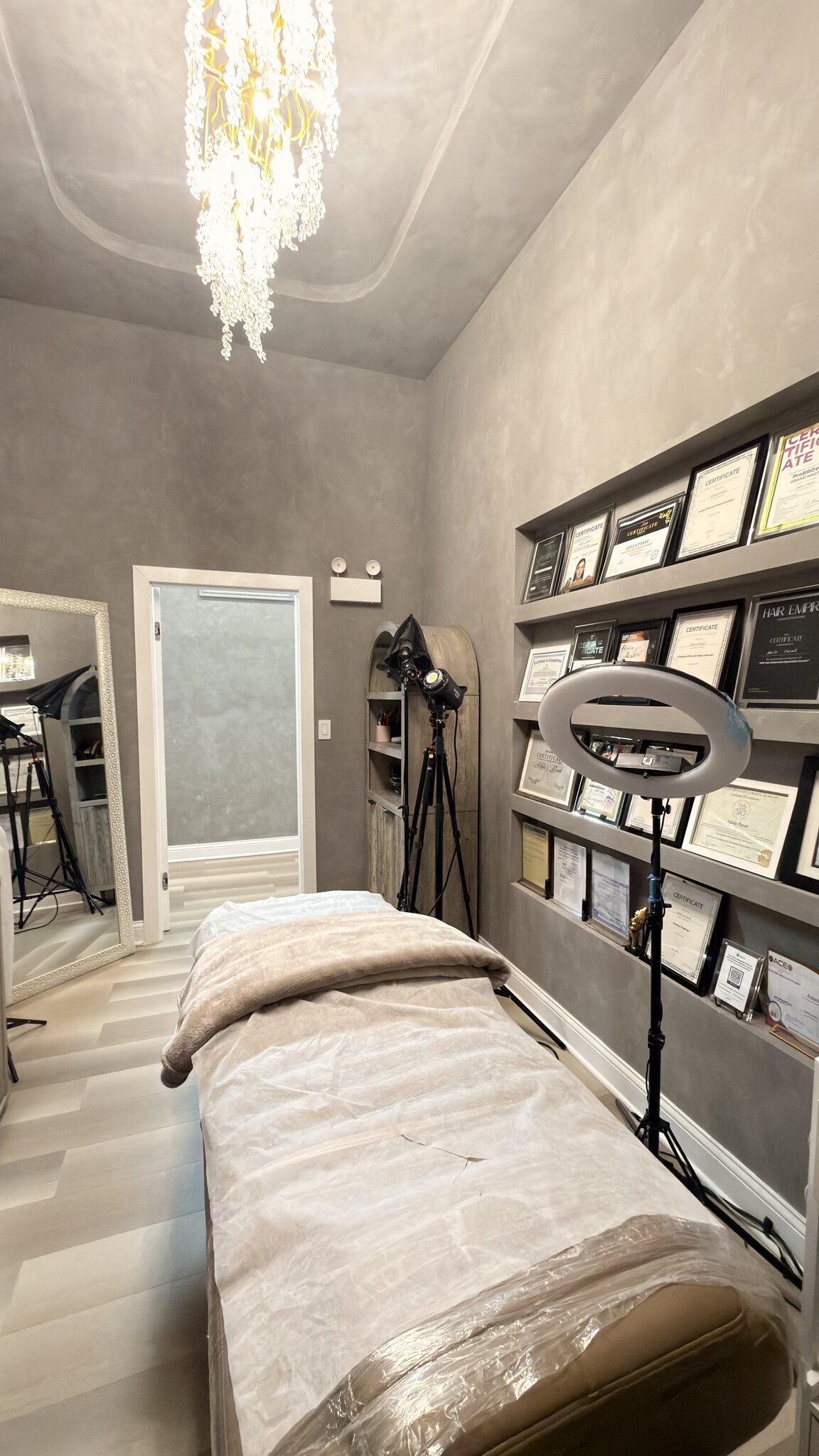 Elegant salon treatment room featuring a massage bed, professional lighting, and framed certificates.