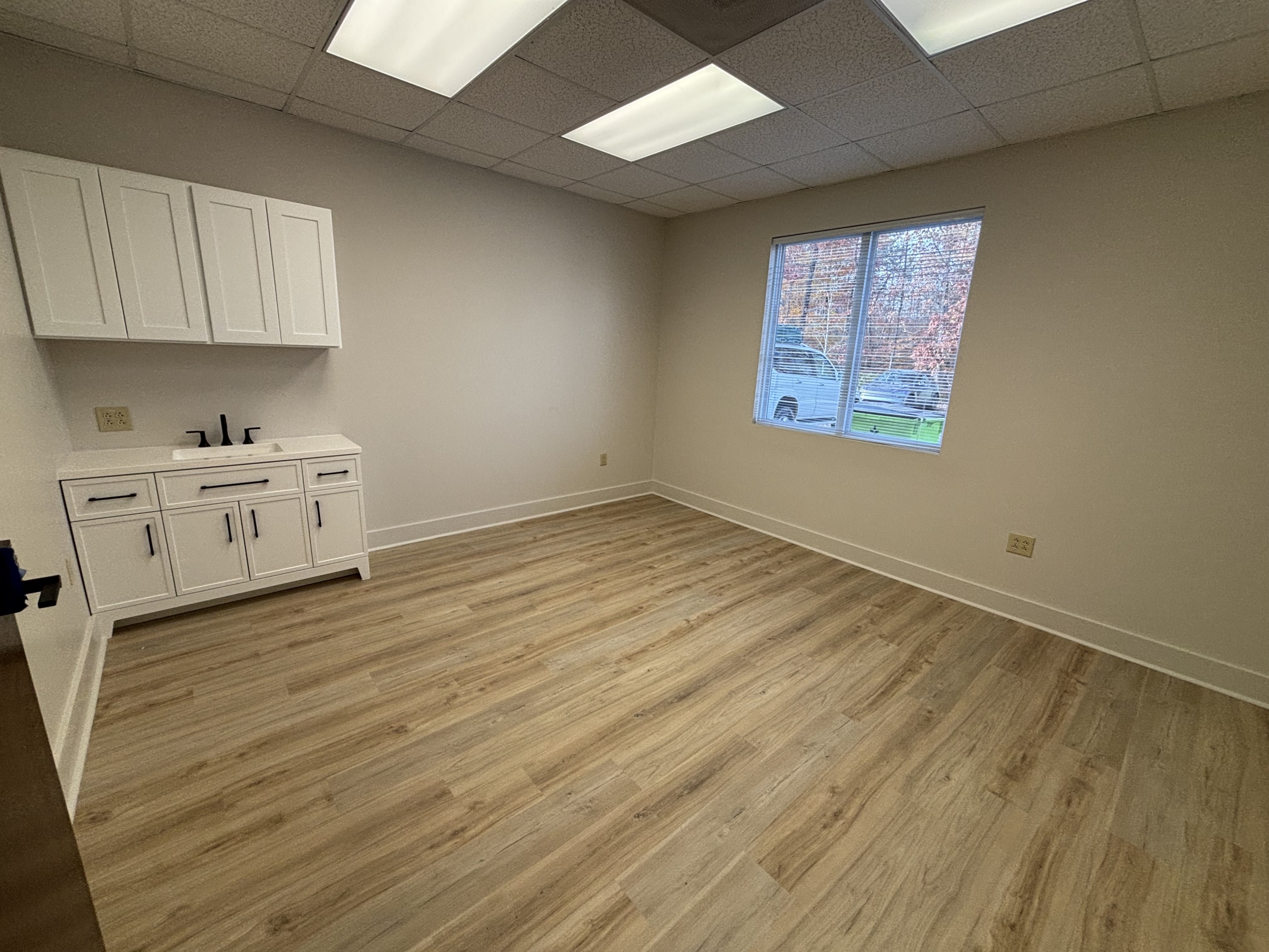 Modern salon rental space with large window and white cabinetry, ideal for beauty professionals seek.