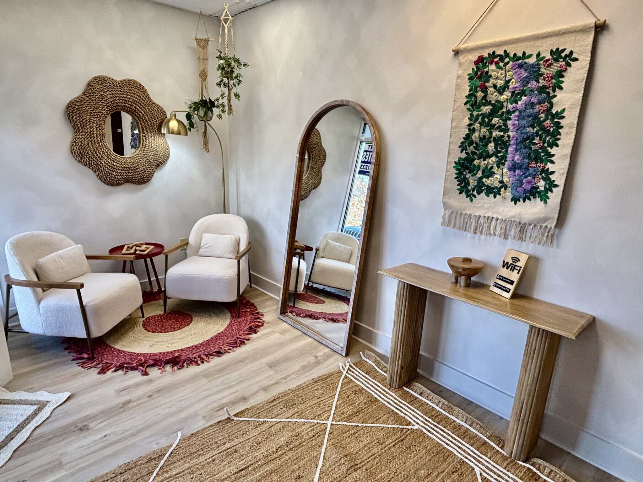 Comfortable salon waiting area with stylish chairs, mirror, and wall art.