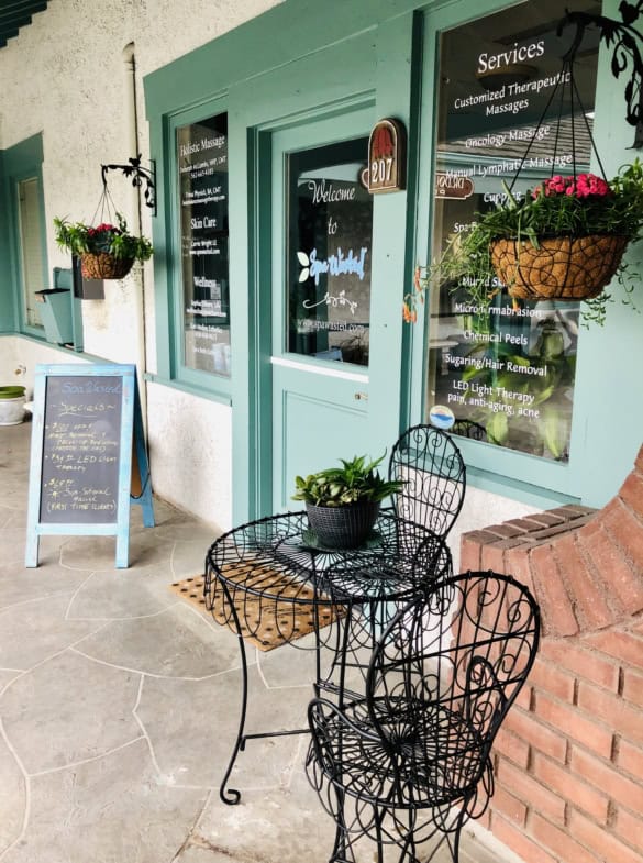 Outdoor seating area at Salon Renter with black wrought iron chairs and potted plants.