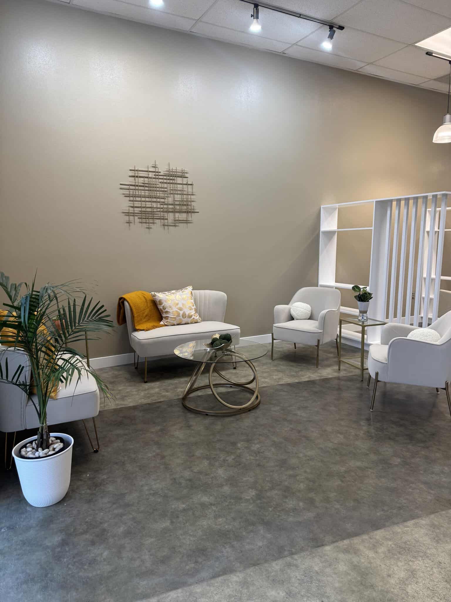 Comfortable salon waiting area featuring stylish white chairs, a cozy sofa with cushions, and decora.