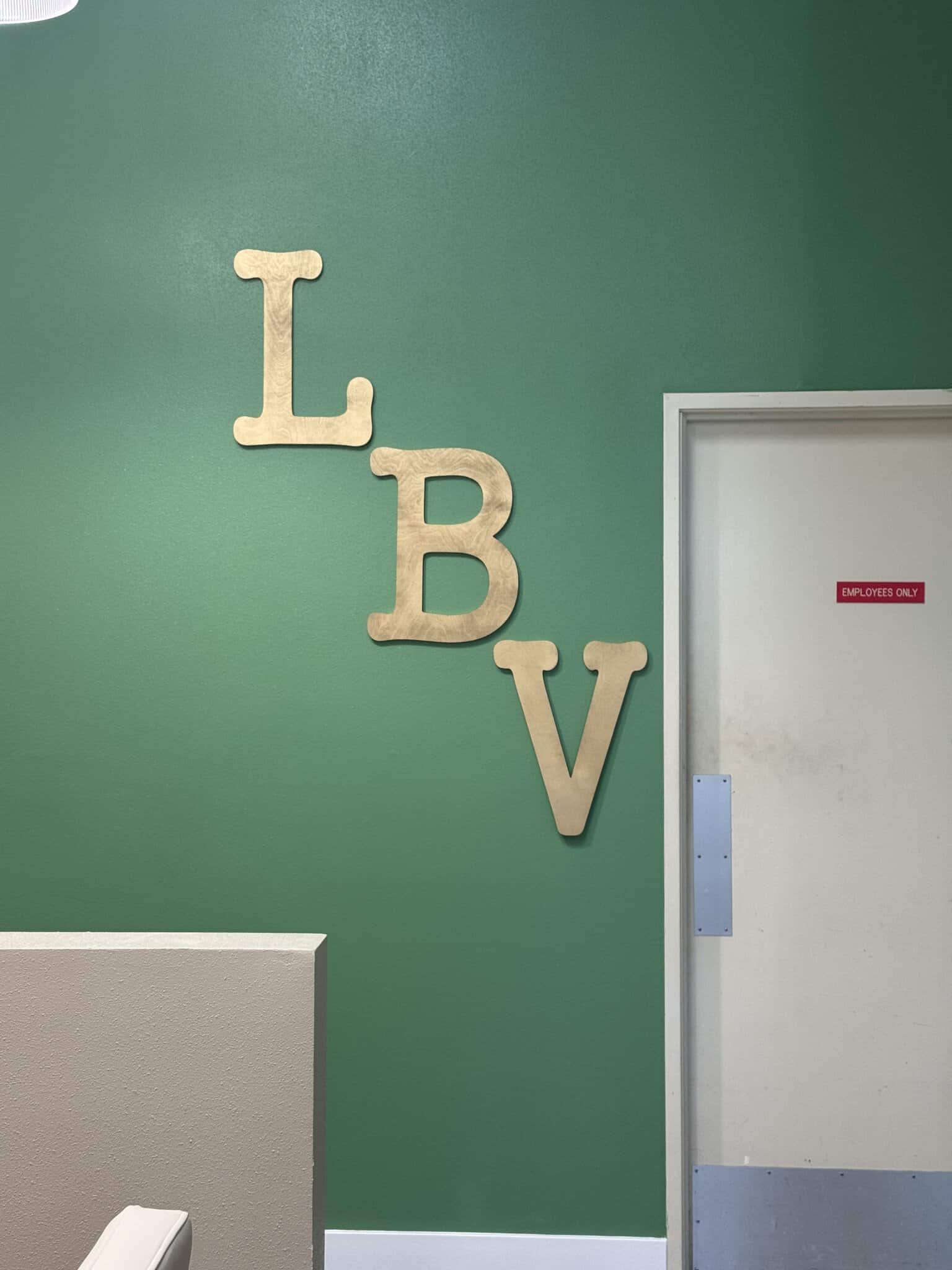 Decorative "LBV" letters on green wall in salon lounge area, modern interior design.