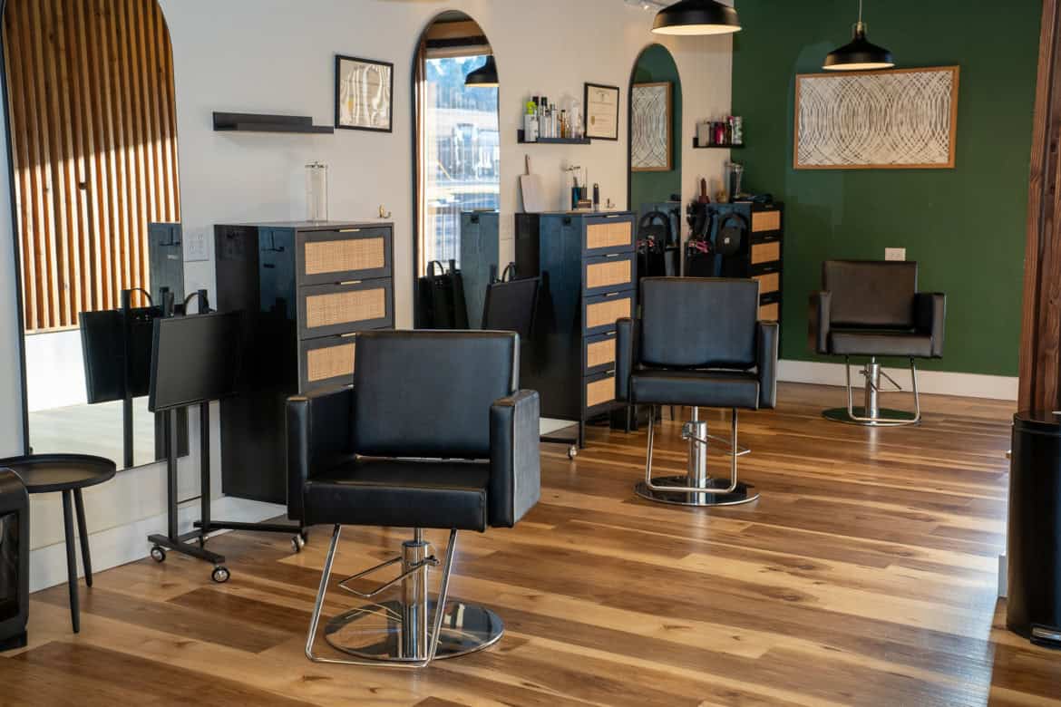 Modern hair salon interior with styling stations, chairs, and decor for hair services.