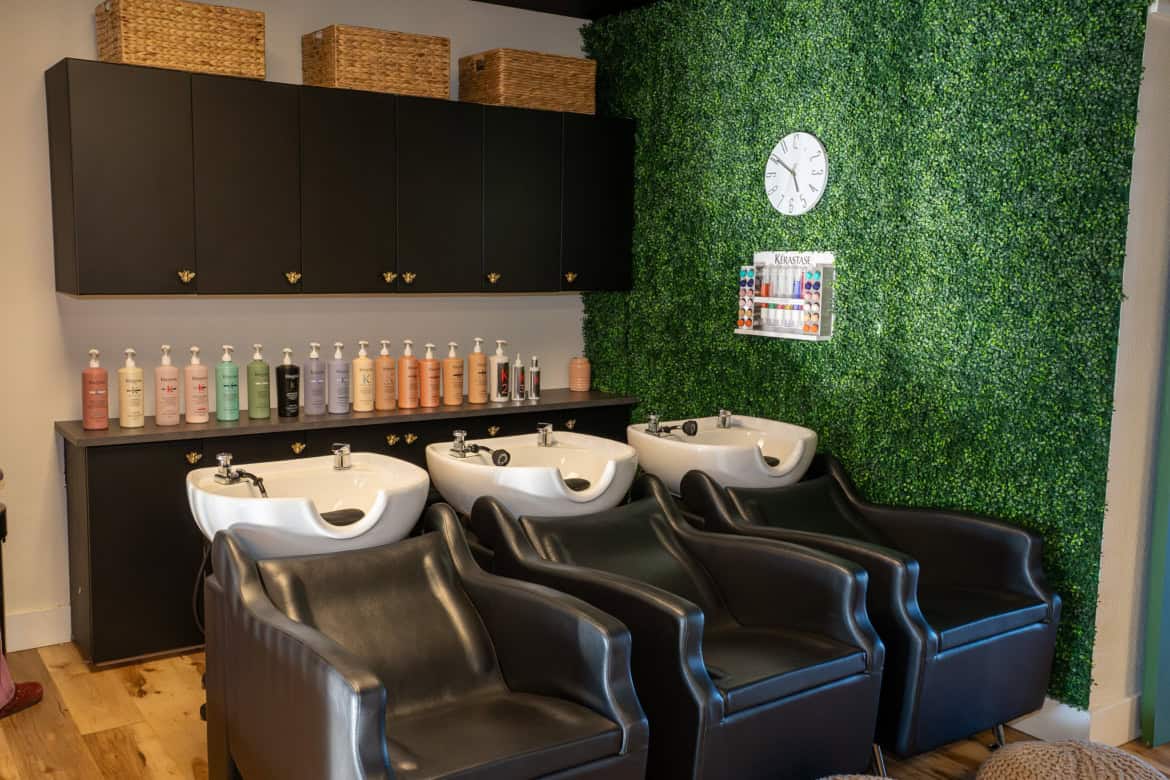 Hair washing station with black chairs and green wall at Salon Renter.
