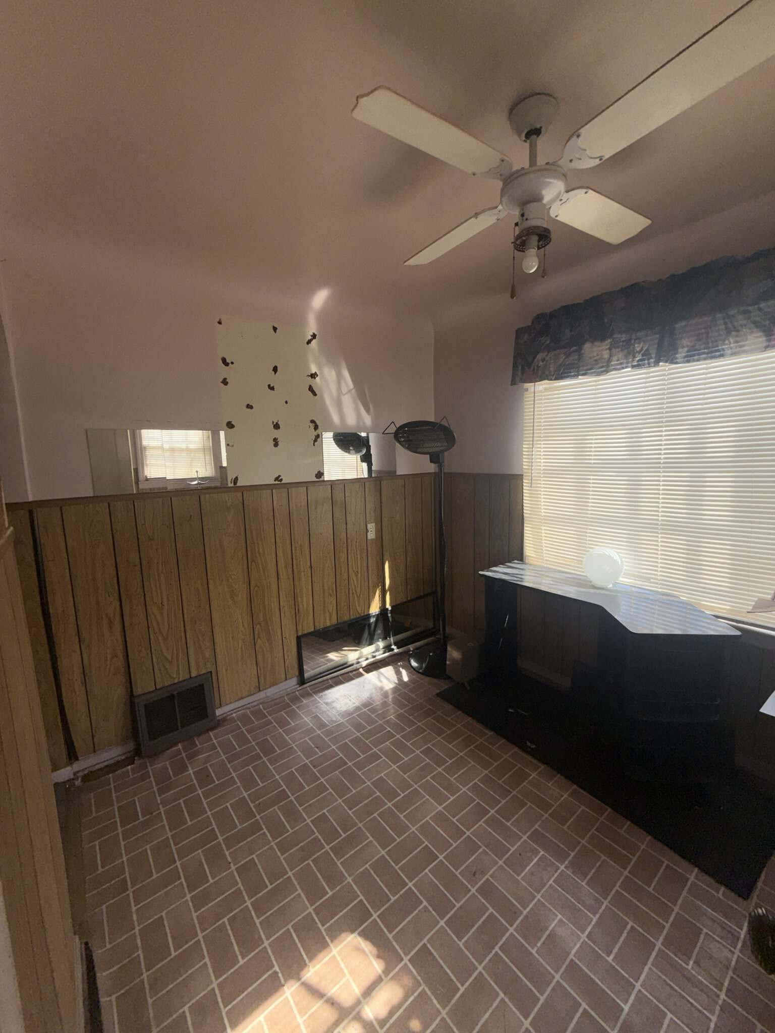 Bright salon space with large window and ceiling fan.
