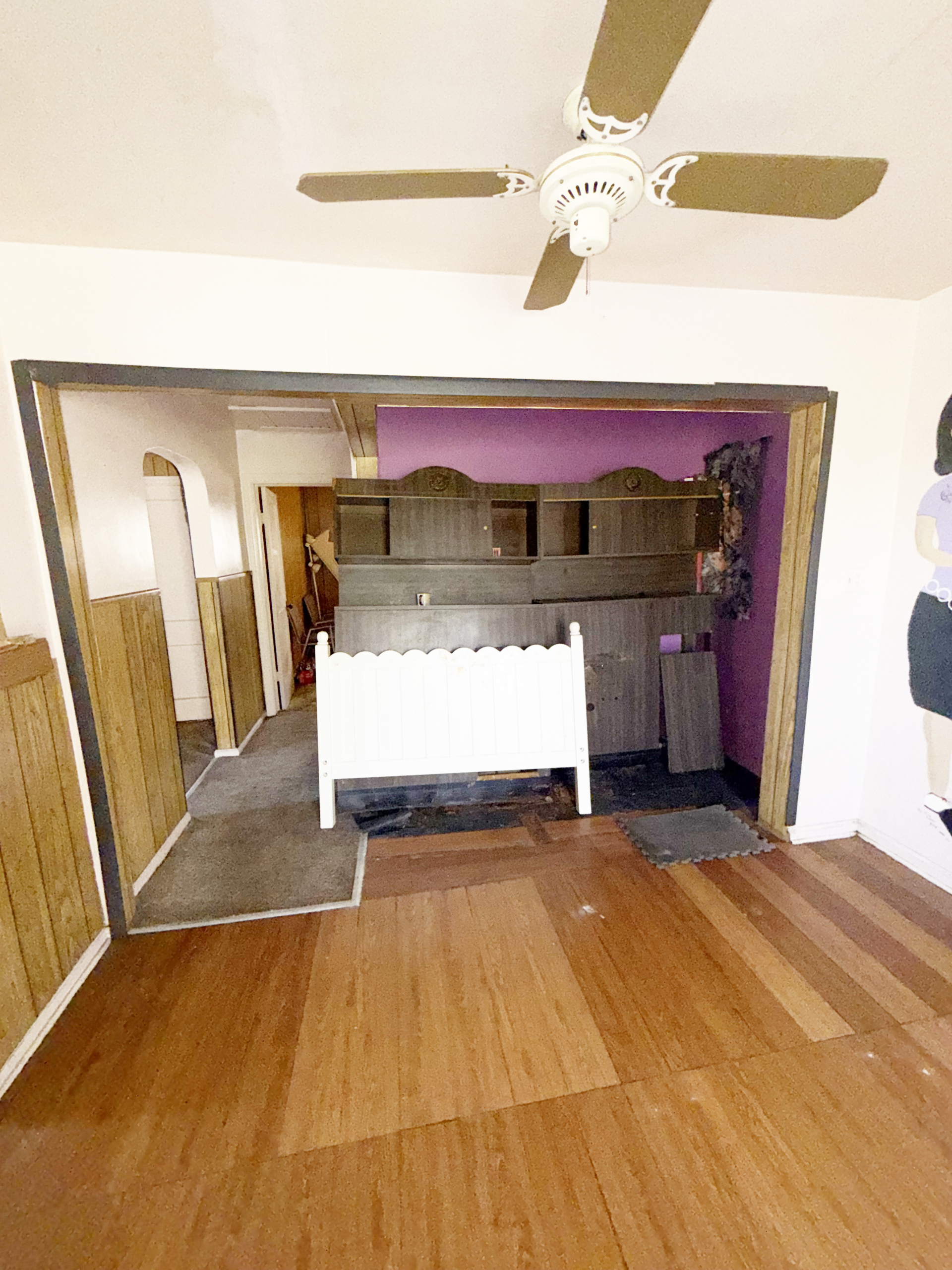 Empty salon space with purple accent wall, ceiling fan, and wooden floors, ideal for salon rental or.
