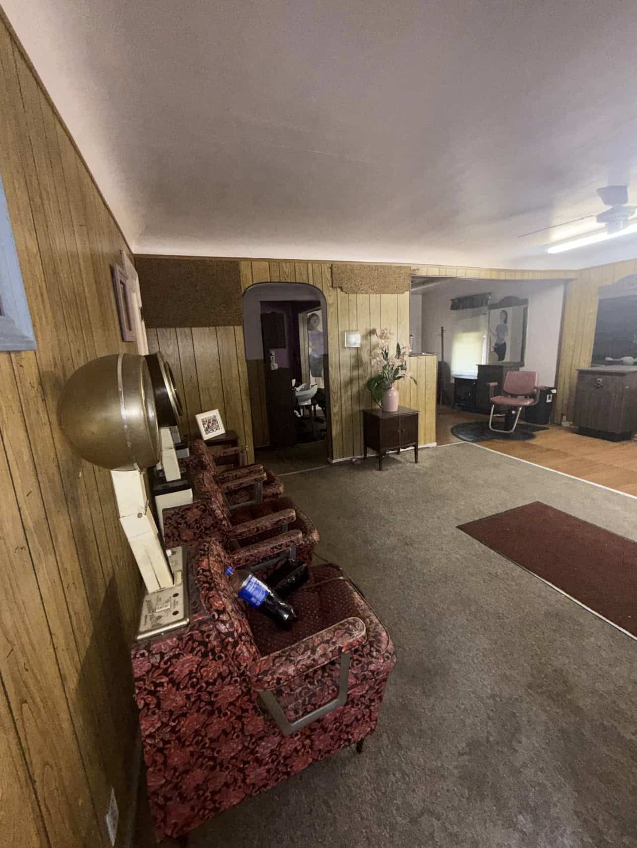 Vintage salon waiting area with floral upholstered chairs and wooden paneling walls. Perfect for rel.