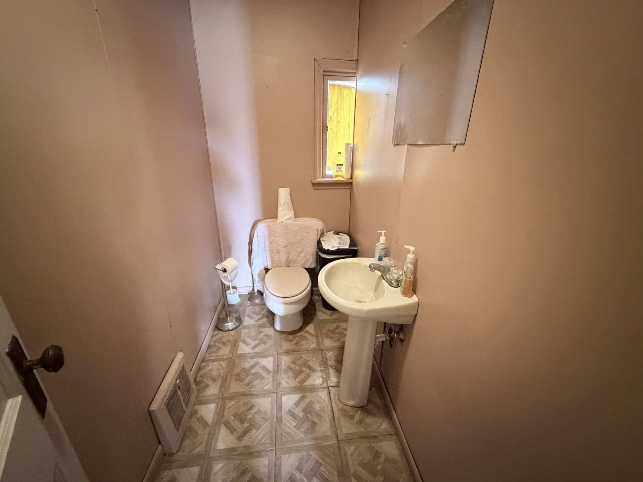 Small bathroom with toilet, sink, and window for natural light.