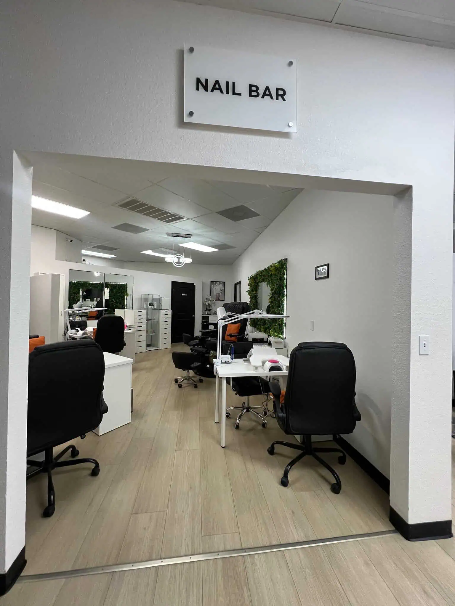 Exterior view of a salon and barber shop with a green awning and open glass door.